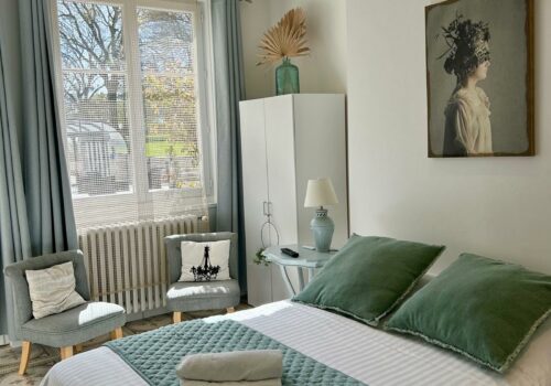 La chambre du petit gîte dans des tons neutres (gris et blanc) avec une touche de vert sauge.