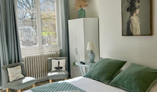 La chambre du petit gîte dans des tons neutres (gris et blanc) avec une touche de vert sauge. 