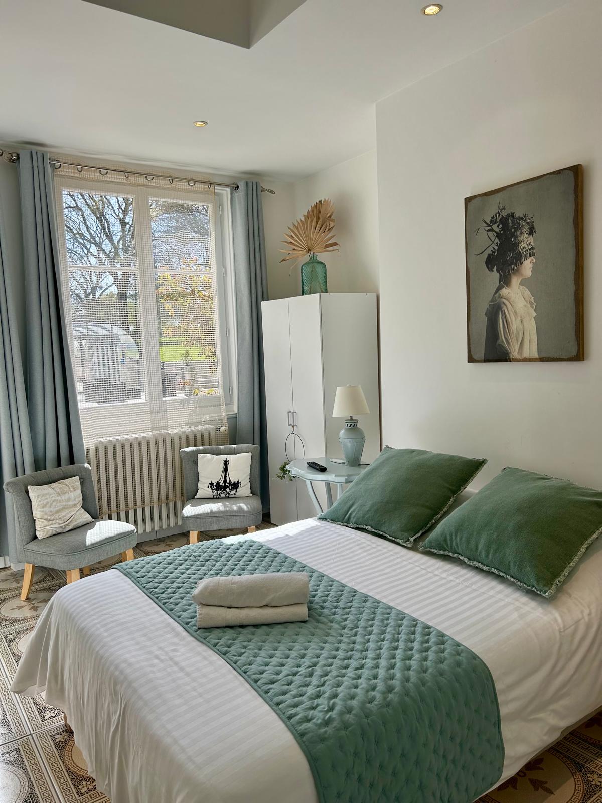 La chambre du petit gîte dans des tons neutres (gris et blanc) avec une touche de vert sauge.