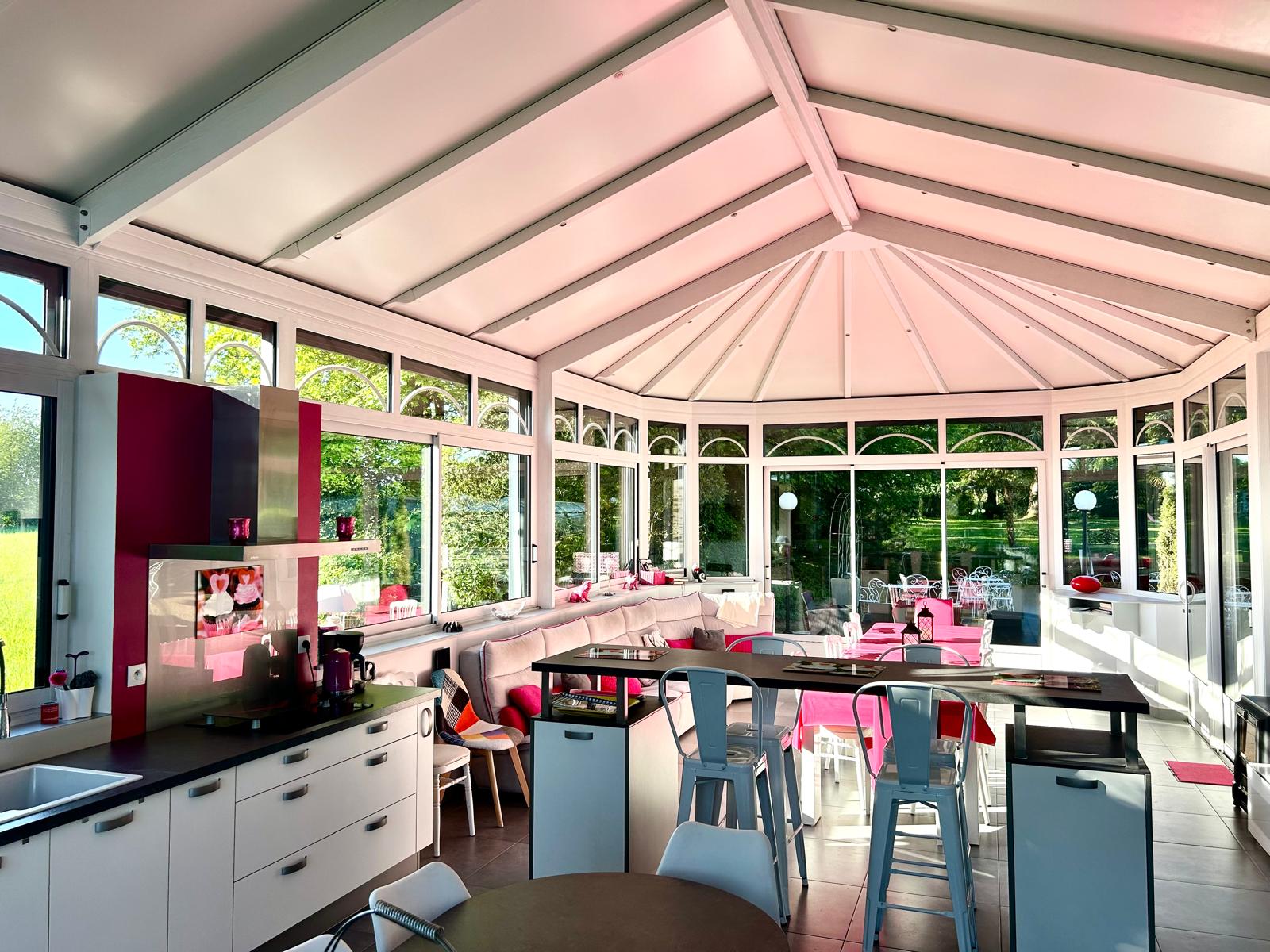 Le gîte Véranda avec un grand salon ainsi qu'une cuisine. Tons rose fuschia.